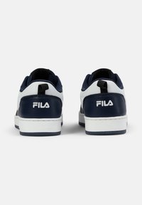 Weiße und marineblaue Sneaker mit Obermaterial aus Leder und Textil. Mit einem schwarzen Zugband, einem auffälligen seitlichen Logo und einer strukturierten Gummi-Außensohle.