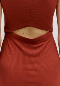 Geribbelde roestkleurige jurk met een uitsnijding in de taille, met een gladde textuur en een figuurnauwsluitend ontwerp.