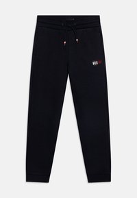 Černé tepláky vyrobené z měkkého materiálu, s elastickým pasem a šňůrkou na stažení, bočními kapsami a malým grafickým logem na stehně.