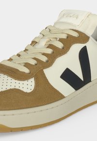 Baskets beige et marron avec une zone d'orteil blanche perforée, des lacets crème et un logo V noir sur le côté, montrant les détails avant et côté.