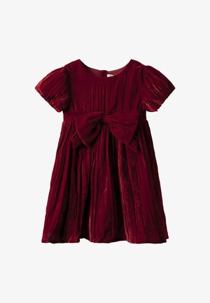 Bársonyos, mélyvörös lányruha rövid puffos ujjakkal, redős szoknyával, és nagy masnival a deréknál.