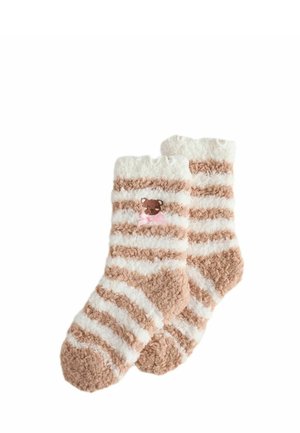 Calcetines suaves y esponjosos con rayas horizontales beige y blancas y una pequeña cara de osito de peluche con un lazo rosa bordado cerca del puño.