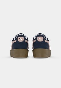 Navy suede sneakers with pale pink accents, white laces, and thick gum rubber soles. Features a logo on the heel and rounded toe design.