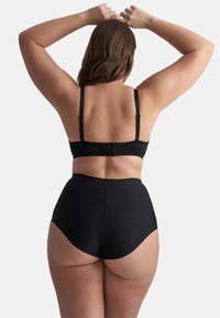 Set di lingerie nero composto da un bralette con spalline regolabili e mutandine a vita alta, realizzato in tessuto morbido con cuciture minime.
