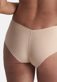 Beige high-waisted ondergoed van gladde stof, met een naadloos ontwerp en een subtiele achternaad voor definitie.