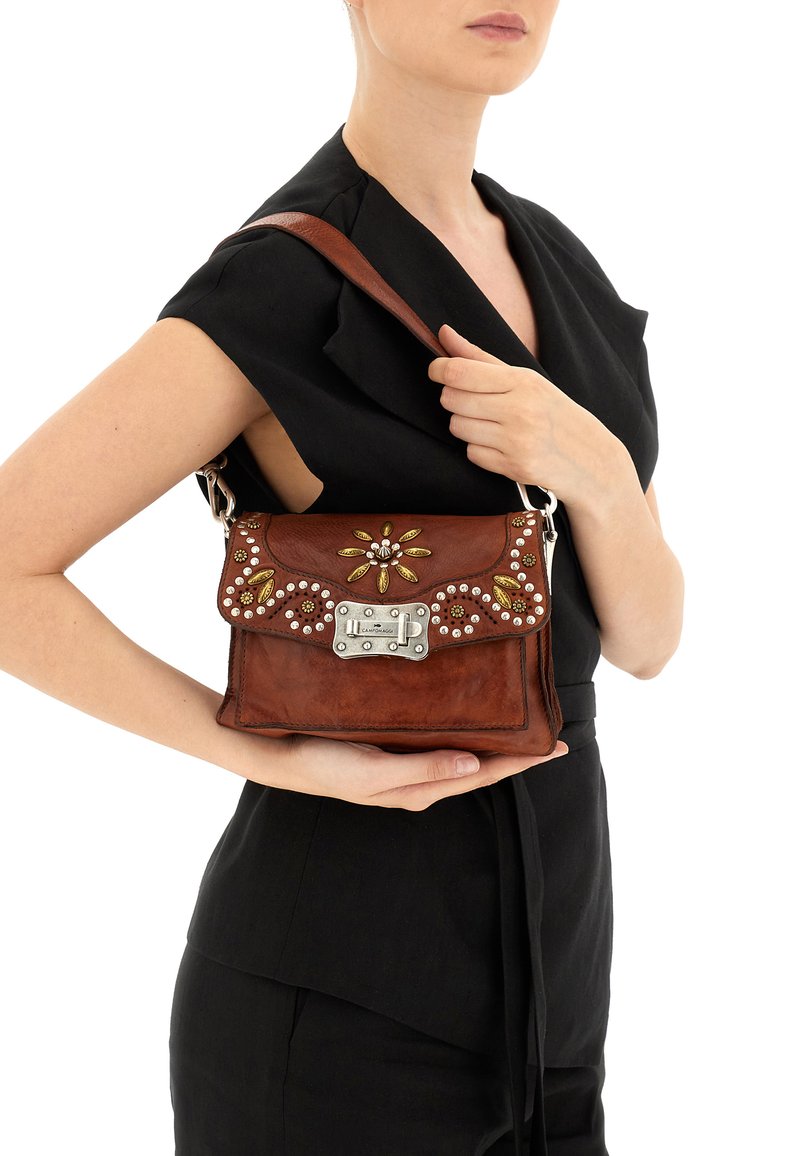 Borsa a tracolla in pelle marrone con accessori in argento, dettagli in metallo decorativi e abbellimenti floreali. Dotata di tracolla e forma rettangolare.