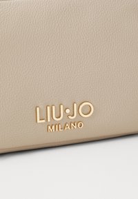 Bežna teksturirana usnjena torba z zlato embosiranim logotipom, ki pravi "LIU·JO MILANO." Preprosta in elegantna zasnova brez dodatnih okraskov.