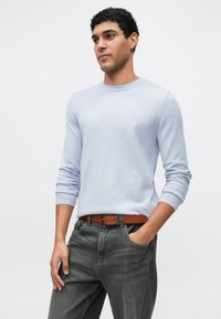 Lichtblauwe trui met lange mouwen en een ronde hals, gecombineerd met grijze spijkerbroek en een bruine riem. Soepele textuur, eenvoudig ontwerp, casual pasvorm.