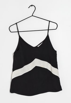 Black sleeveless top with thin straps and a white diagonal chevron stripe across the front, hanging on a black hanger.