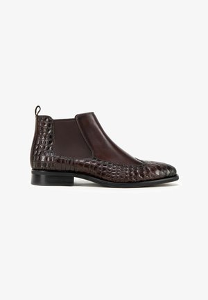 Bottes Chelsea en cuir brun avec un motif embossé crocodile, des panneaux élastiques et un talon bas empilé. Matériaux lisses et texturés combinés.