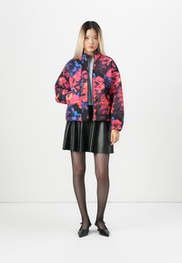Floral quilted bomber jacket in vibrant pink, blue, and black colors; paired with a black leather mini skirt and sheer black tights.