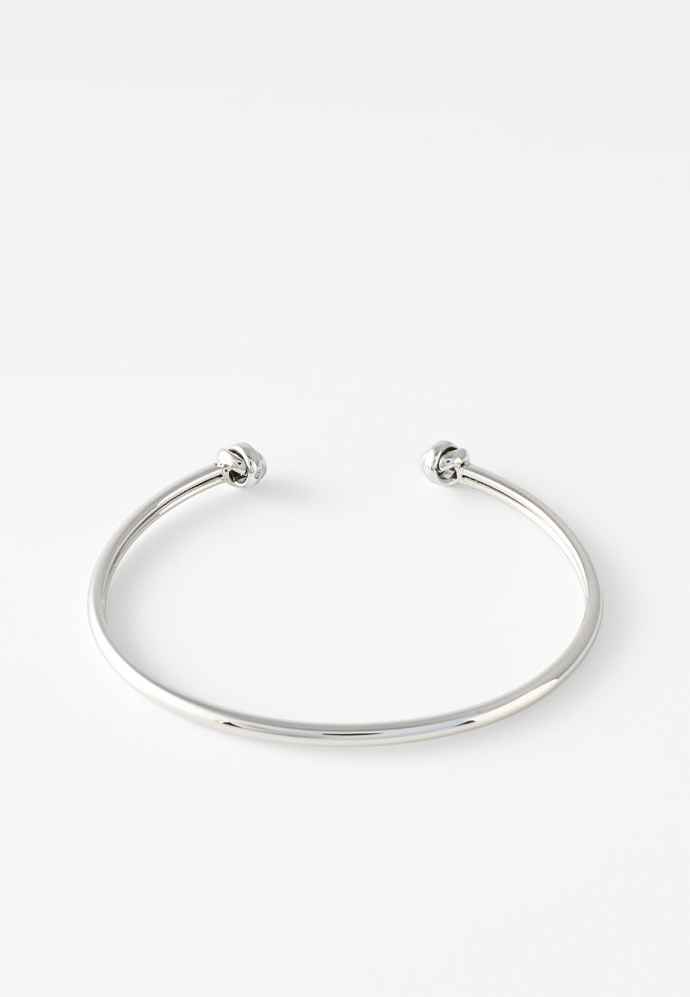 Bracciale cuff in metallo argentato con design minimalista e liscio. Presenta estremità arrotondate, struttura aperta e finitura lucida.