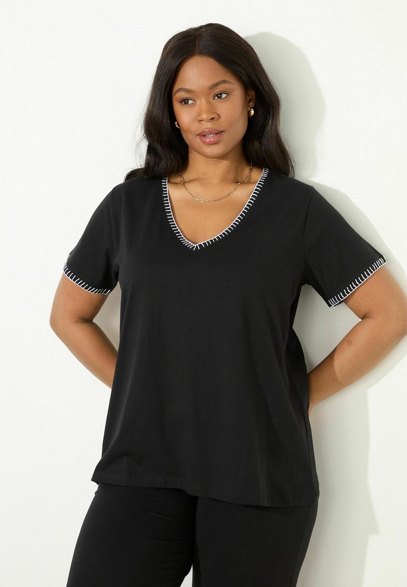 Černé tričko s krátkým rukávem z měkké tkaniny s výstřihem do V a bílým prošíváním kolem límce a rukávů. Uvolněný střih.