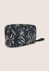 Borsa cosmetica con zip in tessuto blu scuro, caratterizzata da un motivo a foglia astratta bianca, di forma rettangolare con un manico laterale per facilitare il trasporto.