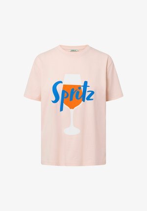 T-shirt en coton rose clair avec un grand texte bleu "Spritz" et un graphique d'une boisson orange dans un verre blanc.