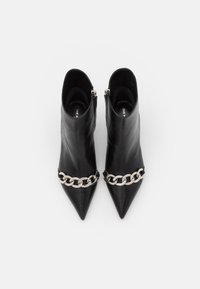 Mustat nahkaiset nilkkurit, joissa on terävä kärki, ja etuosassa on hopeinen ketjuviimeistely sekä sivussa vetoketju.