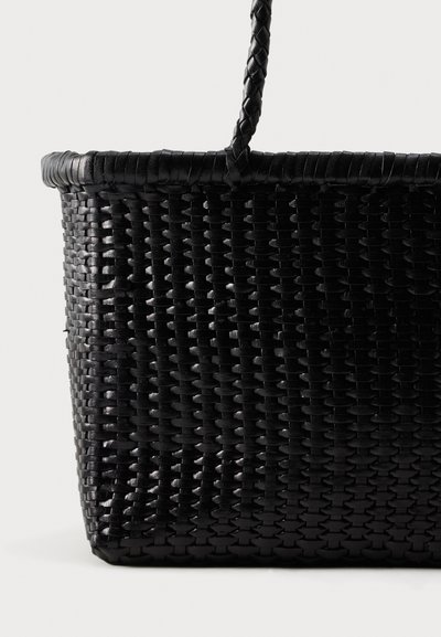 Μαύρο υφαντό καλάθι με μία πλεγμένη λαβή, εμφανίζεται σε απλό φωτεινό φόντο.