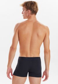 Boxer da uomo neri realizzati in un tessuto morbido, con una vestibilità aderente, un elastico in vita e un design minimalista senza fantasie o dettagli.