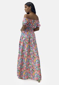 Robe maxi florale avec un design décolleté. Caractéristiques d'un fond bleu avec des fleurs multicolores, une taille smockée et des manches bouffantes.