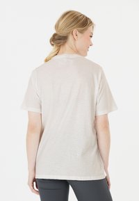 Ljust beige t-shirt med kort ärm, mjuk textur, avslappnad passform, rund halsringning, med en enkel baksida och inga synliga mönster eller dekorationer.