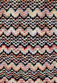 Tissu tricoté présentant des motifs en zigzag dans des teintes multicolores sur fond noir, avec des détails en dentelle et une surface texturée.