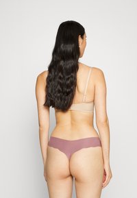 Naadloze bikini onderbroek met kantafwerking, gemaakt van zacht, rekbaar mauve stof. Heeft een low-rise ontwerp en een gladde textuur.