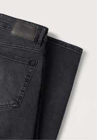 Jean en denim noir avec un patch en cuir, présentant un design classique à cinq poches, une texture lisse et une coupe droite.