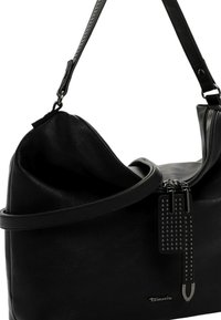 Zwarte leren schoudertas met zilverkleurige studs aan de ritstrekkers en verstelbare schouderband, met het merk "Tamaris" op de voorkant.