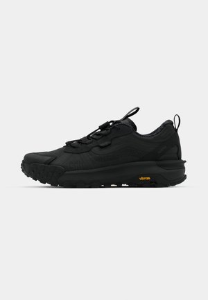 Black hiking shoe with a textured upper, rounded toe, and a cushioned sole. Features a pull tab and elastic laces for a secure fit. Vibram logo.