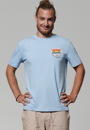 Lichtblauwe katoenen t-shirt met korte mouwen en een ronde halslijn. Heeft een kleurrijke cassettegrafiek op het gebied van de borstzak.