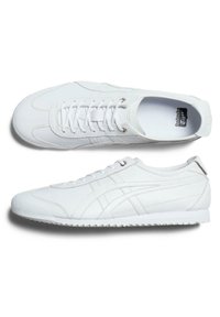 Białe sportowe buty wykonane ze skóry z gładką teksturą, o niskim profilu, okrągłym nosku i minimalistycznym designie, z subtelnym brandingiem.