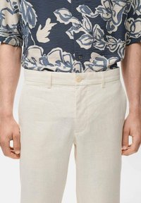 Witte linnen broek met een knoopsluiting. Gekocht met een blauw bloemenpatroon kortarmshirt met lichtere accenten.