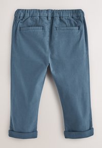 Pantaloni blu con vita elasticizzata, risvolti arrotolati e due tasche a filetto sul retro, mostrati da dietro su uno sfondo neutro.