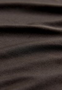 Tumši brūns audums ar gludu, strukturētu virsmu un smalku pinuma rakstu, kas atspoguļo maigas krokas un dažādas gaismas atstarošanas.