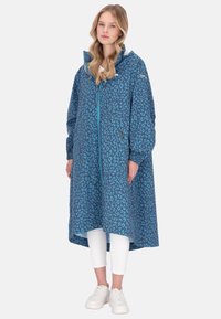 Sininen leopardikuvioinen takki, jossa on korkea kaulus, pitkät hihat ja pidempi takaosa. Valmistettu teksturoidusta materiaalista, edessä vetoketjukiinnitys.