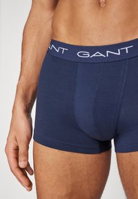 Sötétkék boxer alsónadrág, puha tapintással, fehér GANT logóval az elasztikus derékpánton és kényelmes, testhezálló fazonnal.