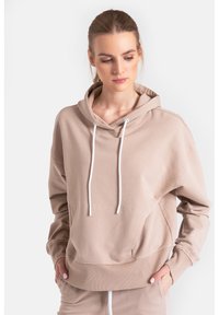 Beżowa bluza z kapturem, z przednią kieszenią kangurką, sznurkiem w kapturze, ściągaczami na rękawach i u dołu. Miękki materiał o luźnym kroju.