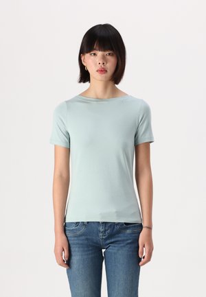 Ljusblå t-shirt med korta ärmar i mjukt material, med en vid halsringning och figurnära skärning, tillsammans med blå jeans.