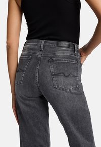 Dunkelgraue Jeans aus Denim mit leicht gefauschtem Muster, einer hohen Taille, Kontrastnähten und zwei Gesäßtaschen mit einem dezenten Design.