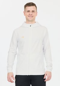 Hvid zip-up hoodie lavet af letvægtsstof, med hætte, lange ærmer og et lille guld "FZ" logo på brystet.