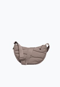 Puolikuun muotoinen taupen värinen olkalaukku, jossa on pehmustettu, tikattu pinta ja säädettävä kangashihna valkoisella taustalla.