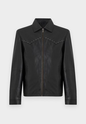Chaqueta de cuero negro con cremallera frontal, cuello puntiagudo, mangas largas, bolsillos laterales y tachuelas plateadas a lo largo de las costuras del pecho.