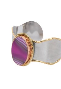 Hopeakauha rannekoru aaltoilevalla muotoilulla, jossa on pyöreä, violetti, raidallinen kivi asetettuna kultasävyiseen metalliin. Harjattu metallipinta.