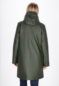 Olive zaļš ūdensizturīgs mētelis ar kapuci, kam ir gluda, spīdīga virsma un brīva forma. Aizmugurējā skata attēlo šuvju detaļas un garas piedurknes.