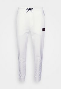 Witte joggingbroek met zijzakken, elastische tailleband en zwarte trekkoorden. Heeft een rood en zwart logo op het linkerpijp.