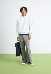 Gray hoodie with drawstrings, black pants, black backpack, and sneakers. Simple design, casual fit, textured fabric, and medium weight.