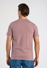 T-shirt med korta ärmar och rund hals i färgen dammrosa, gjord av mjukt tyg med en slät yta utan synliga mönster eller detaljer.