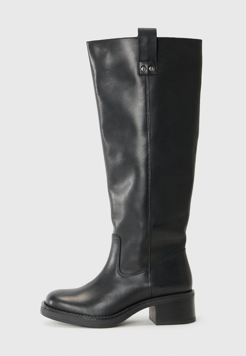 Bota de couro preta até ao joelho com bico arredondado, detalhes costurados e um salto bloco. Uma pequena aba está localizada no topo.