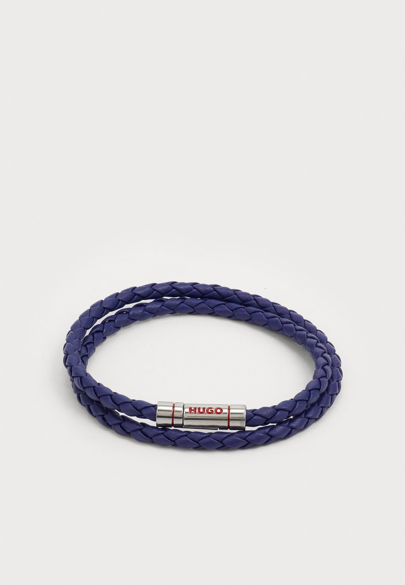 Bracciale intrecciato in pelle viola con una chiusura metallica con accenti rossi e branding 'HUGO'. Texture compatta e liscia.
