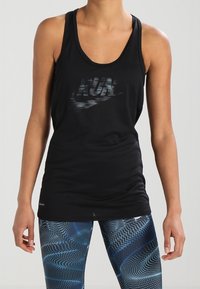 Débardeur de sport noir avec un col en U, arborant le mot « RUN » en impression réfléchissante. Porté avec un legging bleu à motifs courbes.